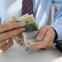 Dłonie liczą banknoty złotowe. Wkrótce jawność wynagrodzeń 2026, więc transparentność finansowa staje się kluczowa.