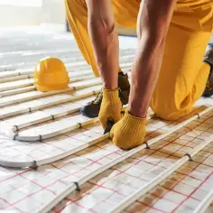 Instalator układa rury do ogrzewania podłogowego. Kluczowe jest odpowiednie rozmieszczenie, by obliczyć ile rury na m2 ogrzewania podłogowego.