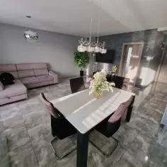 Nowoczesny salon z jadalnią, kanapą, stołem i kwiatami.