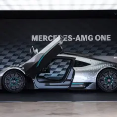 Srebrny Mercedes-AMG ONE z otwartymi drzwiami i maską, prezentujący swoje futurystyczne linie i sportowy charakter.
