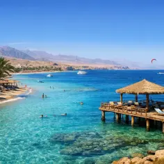 Piękna plaża w Marsa Alam z palmami, turkusową wodą i pomostem. Uważaj na słońce i korzystaj z cienia!