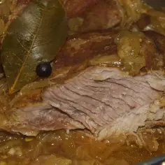 Duszony udziec z indyka w sosie własnym, z liściem laurowym i zielem angielskim, wygląda niezwykle apetycznie.