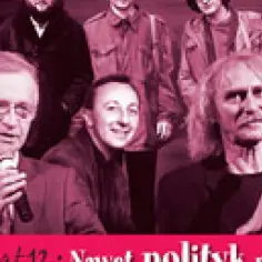 Grupa mężczyzn, jeden z mikrofonem, w teatralnym świetle. Wygląda na parodię polityków.