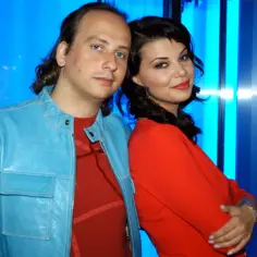 Edyta Górniak z mężem, którego mąż edyty górniak nie żyje, na tle niebieskich paneli.