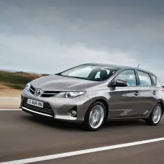 Szary Toyota Auris 2015 pędzi po drodze, krajobraz rozmywa się w tle.