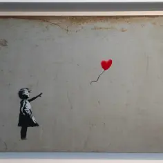 Banksy jak wygląda: dziewczynka w czarnej sukience sięga po czerwony balon w kształcie serca.