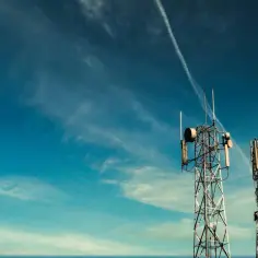 Dwa maszty telekomunikacyjne, prawdopodobnie nadajniki T-Mobile, na tle błękitnego nieba z chmurami.