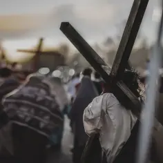 Droga Krzyżowa: postać w koronie cierniowej niesie krzyż, a za nią idzie tłum. W tle widać kolejne krzyże, symbolizujące wszystkie stacje.