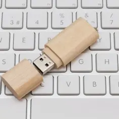 Drewniany pendrive leży na klawiaturze. Prosty sposób, jak zapisać coś na pendrive, to skopiować pliki i wkleić je na podłączonym urządzeniu.