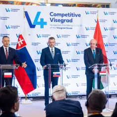Liderzy Grupy Wyszehradzkiej podczas konferencji prasowej. Na pierwszym planie politycy, za nimi flagi Polski, Słowacji, Węgier i Czech.