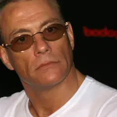 Jean-Claude Van Damme w okularach, w białej koszulce, na tle logo "bodog FIGHT".