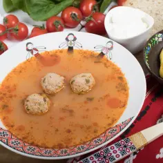 Aromaticzna zupa romana z klopsikami, podana z chlebem, śmietaną i pikantną papryką.