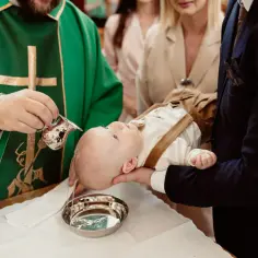 Chrzest dziecka w kościele: kapłan polewa głowę niemowlęcia wodą święconą. To ważny moment, który nie trwa długo.