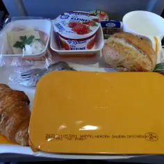 Taca z jedzeniem w samolocie: jogurt, bułka, croissant, ser. Ile słodyczy można przewieźć samolotem?