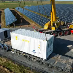 Dźwig podnosi kontener z bateriami do instalacji fotowoltaicznej. Transport przesyłowy w trakcie rozładunku.