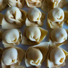 Rządki surowego tortellini, małych pierożków z ciasta makaronowego, gotowe do gotowania.