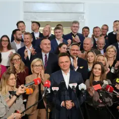 Grupa posłów Polski 2050, w tym Szymon Hołownia, otoczona przez dziennikarzy z mikrofonami.
