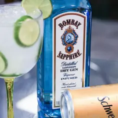 Idealne proporcje gin tonic: szklanka z lodem i limonką, butelka Bombay Sapphire i puszka Schweppes.