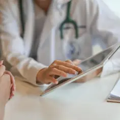 Lekarz wyjaśnia pacjentowi, jak wyliczyć wynagrodzenie chorobowe, korzystając z tabletu.