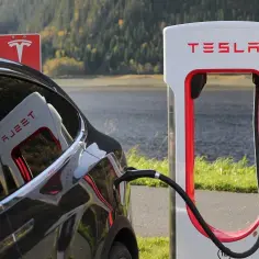 Czarna Tesla podłączona do ładowarki. To pokazuje, że Tesla nie potrzebuje benzyny, a czerpie energię z prądu.