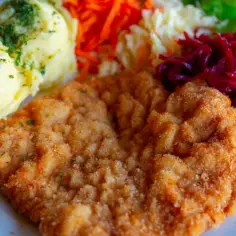 Kotlet schabowy w panierce z ziemniakami i surówkami.