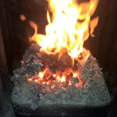 Piec na ekogroszek z zaschniętym miałem węglowym i płomieniami.