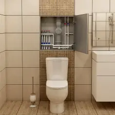 Łazienka z widocznymi rurami w szafce nad toaletą, umywalką i grzejnikiem.