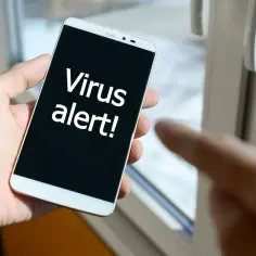 Dłoń trzyma smartfon z komunikatem "Virus alert!". Czas zainstalować antywirus na telefon.