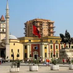 Plac Skanderbega w Tiranie, z meczetem i wieżą zegarową. Zastanawiasz się, ile trwa lot do Albanii z Gdańska?