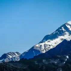 Majestatyczne szczyty Alp, pokryte śniegiem, zapraszają na tour du Mont Blanc. Niebo błękitne, chmury tańczą wokół gór.