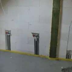 Ściana z bloczków z widocznymi bruzdami pod kable i instalacją wodną. Przygotowania do montażu urządzeń.