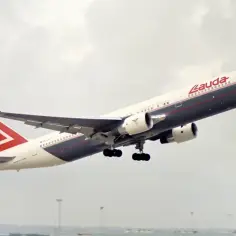 Samolot Lauda Air wznosi się na tle pochmurnego nieba.
