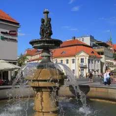 Fontanna na Rynku Kościuszki w Białymstoku, z widocznymi kawiarniami i kościołem w tle.