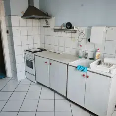 Kuchnia do remontu w Legnicy. Białe płytki, stara kuchenka i zlew. Idealne miejsce, by dowiedzieć się, jak dostać mieszkanie do remontu Legnica.