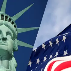 Głowa Statuy Wolności i amerykańska flaga na tle nieba. Zastanawiasz się, ile kosztuje bilet lotniczy do USA?