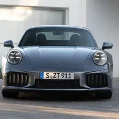 Szary Porsche 911 Turbo S z charakterystycznymi okrągłymi światłami i masywnym grillem, gotowy do jazdy.