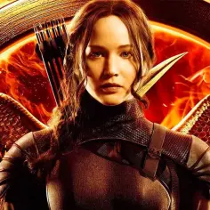 Katniss Everdeen z łukiem i strzałami, w zbroi z piórami, na tle płomieni. Gdzie obejrzeć Igrzyska Śmierci?