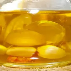 Słoik z oliwą i ząbkami czosnku, idealny do przygotowania aromatyzowanej oliwy czosnkowej i ziołowej bez ryzyka botulizmu.