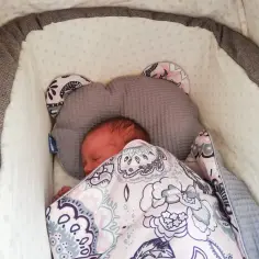 Słodki noworodek śpi w wózku, otulony kocykiem z wzorem. To pewnie jego pierwszy spacer z noworodkiem, pełen spokoju i beztroski.