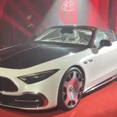 Biały kabriolet Maybach na czerwonym dywanie, prezentowany przez mężczyznę w garniturze. To najdroższy Mercedes, symbol luksusu i prestiżu.