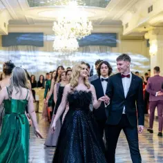 Młoda para idzie na bal. Czy w szkole zaocznej jest studniówka? Eleganckie stroje, błyszczące suknie i garnitury świadczą o wyjątkowej okazji.