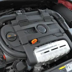 Silnik 1.4 TSI z widocznym logo VW. Widoczne elementy układu dolotowego i osłony silnika.