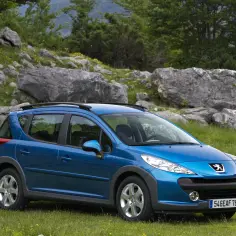 Niebieski Peugeot 207 1.6 HDi na tle skalistego, zielonego krajobrazu.