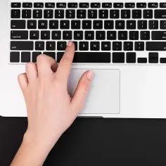 Dłoń naciska klawisz "C" na klawiaturze laptopa, pokazując, jak odblokować klawiaturę w laptopie.