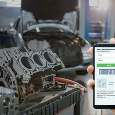 Naprawa Toyoty z błędem C1201. Na ekranie telefonu widoczny kod błędu i części silnika.