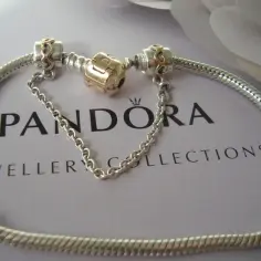 Srebrny łańcuszek zabezpieczający Pandora z złotym elementem. Dowiedz się, jak założyć łańcuszek zabezpieczający Pandora, by chronić swoje cenne charmsy.