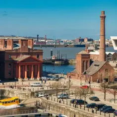 Albert Dock w Liverpoolu, gdzie jest? Żółty amfibia wjeżdża do wody, a w tle widać nowoczesne budynki i zabytkowe ceglane magazyny.