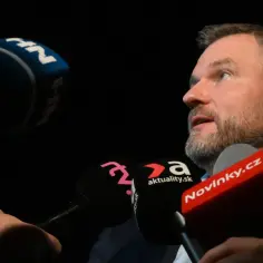 Prezydent Słowacji udziela wywiadu, otoczony przez mikrofony mediów, w tym Novinky.cz.