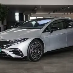 Srebrny Mercedes EQE, lśniący w salonie, z eleganckimi felgami i nowoczesnym designem.