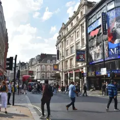 Tętniący życiem londyński **west end** z billboardem "Les Misérables" i ludźmi spacerującymi po ulicy.